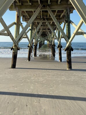 A wooden pier structure with a clear view of the ocean and sandy beach. - Harbor Lights Resort Waterfront Pool Dock (Oak Island)