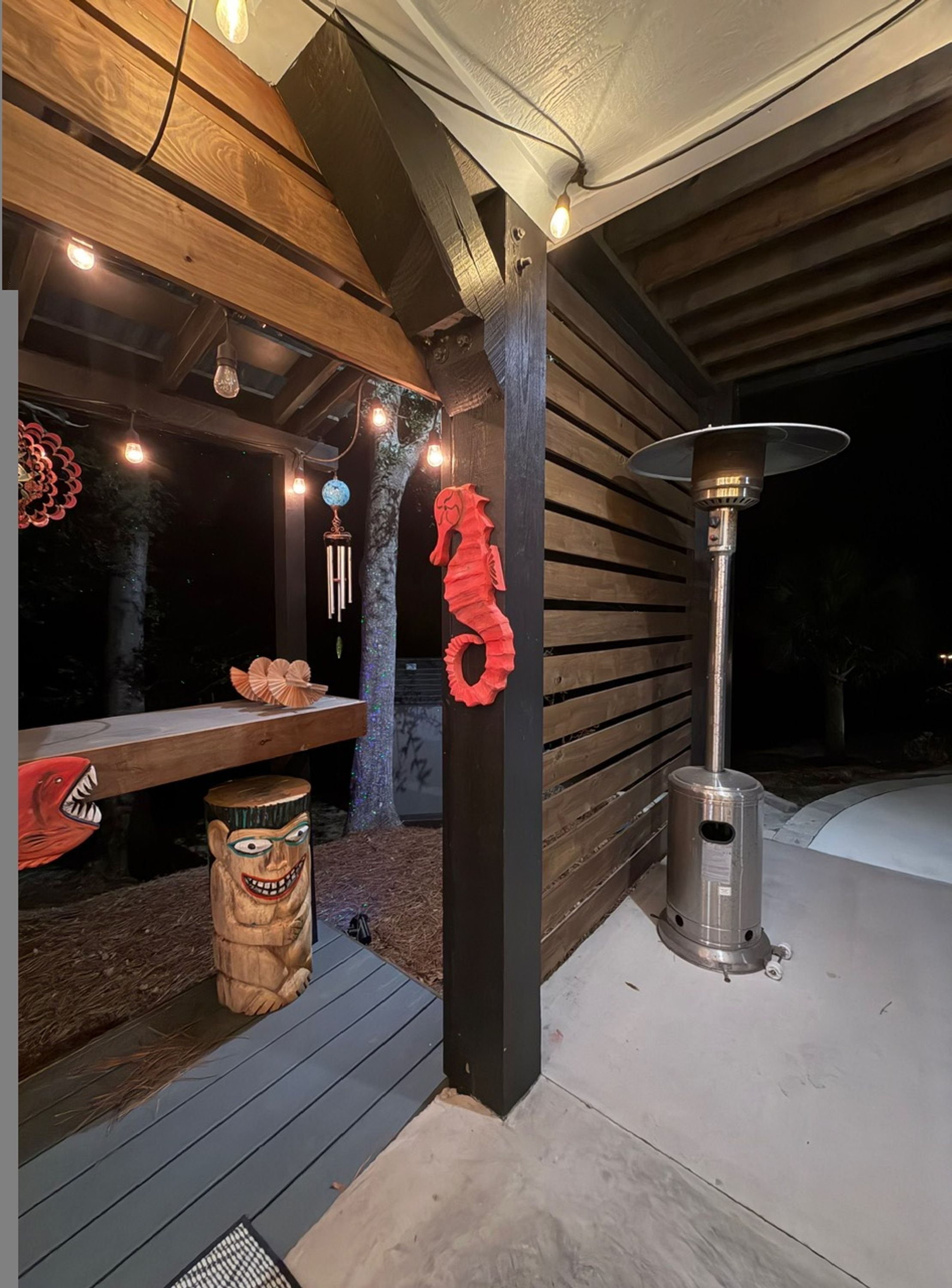 Un espacio de patio al aire libre con un banco de madera, elementos decorativos y un calentador portátil.