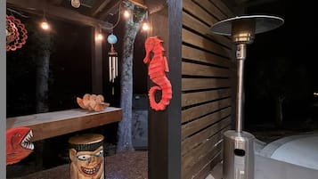 Un espacio de patio al aire libre con un banco de madera, elementos decorativos y un calentador portátil.