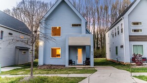 A two-story residential building with a porch, a small garden, and a clear sky. - Quiet Charlotte Home, Sleeps 8, Near Uptown (Charlotte)