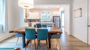 A modern kitchen with a central island, a dining area with chairs, and a view into the living space. - Quiet Charlotte Home, Sleeps 8, Near Uptown (Charlotte)