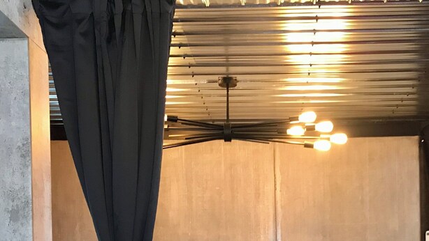 A bed with a patterned headboard, a bedside table with a lantern, and a curtain. - 163 au coeur du centre-ville! (Drummondville)