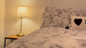 A bed with a floral bedspread, a nightstand with a lamp, and a wall with a floral-patterned pillow. - 163 au coeur du centre-ville! (Drummondville)
