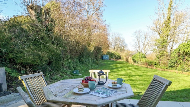 A wooden outdoor table with chairs, a bowl of fruit, a mug, and a lantern. - The Pebble (Dorchester)