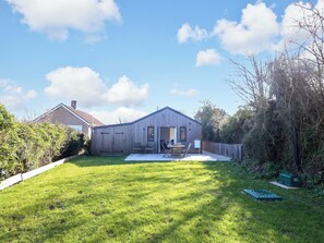 A wooden house with a fenced backyard, a patio with chairs, and a lawn. - The Pebble (Dorchester)