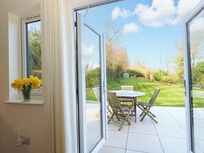 A room with a sliding glass door leading to a patio with a table and chairs. - The Pebble (Dorchester)