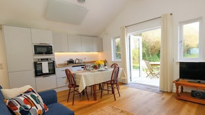 A compact living space with a kitchen, dining area, and a TV. - The Pebble (Dorchester)