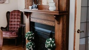 A room with a wooden fireplace, a red upholstered chair, and a door with a glass panel. - The Martin House | Family Getaway Near Shawnee (Elizabethtown)