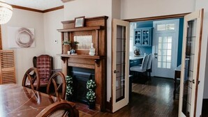 A dining room with a wooden table and chairs, a fireplace, and a view into a kitchen area. - The Martin House | Family Getaway Near Shawnee (Elizabethtown)
