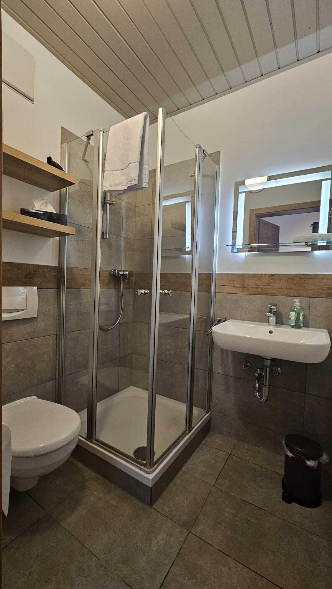 A modern bathroom with a glass-enclosed shower, a toilet, a sink, and a bidet.