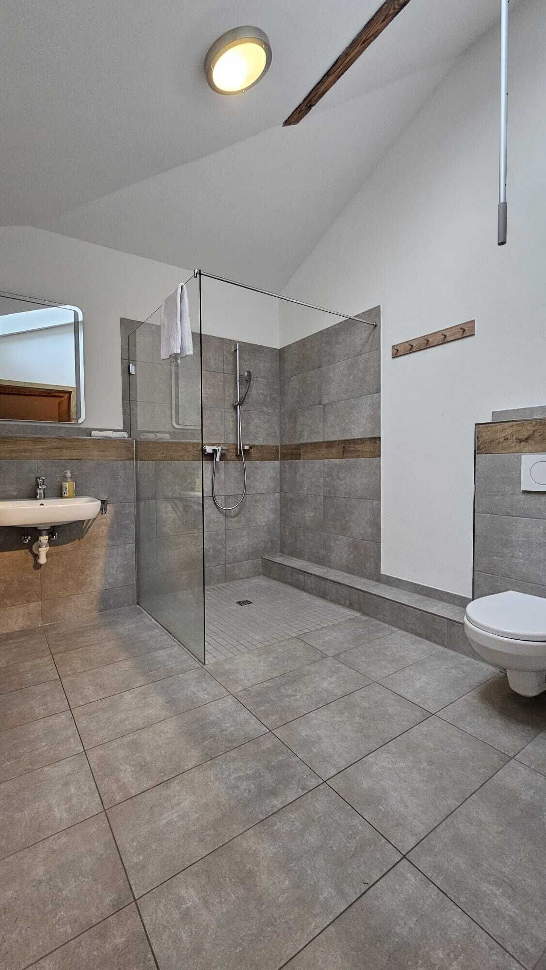 Un baño moderno con cabina de ducha de vidrio, un lavabo e inodoro.