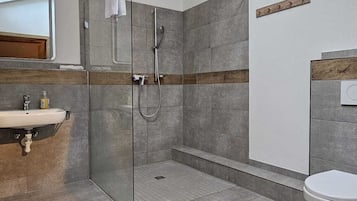 Un baño moderno con cabina de ducha de vidrio, un lavabo e inodoro.