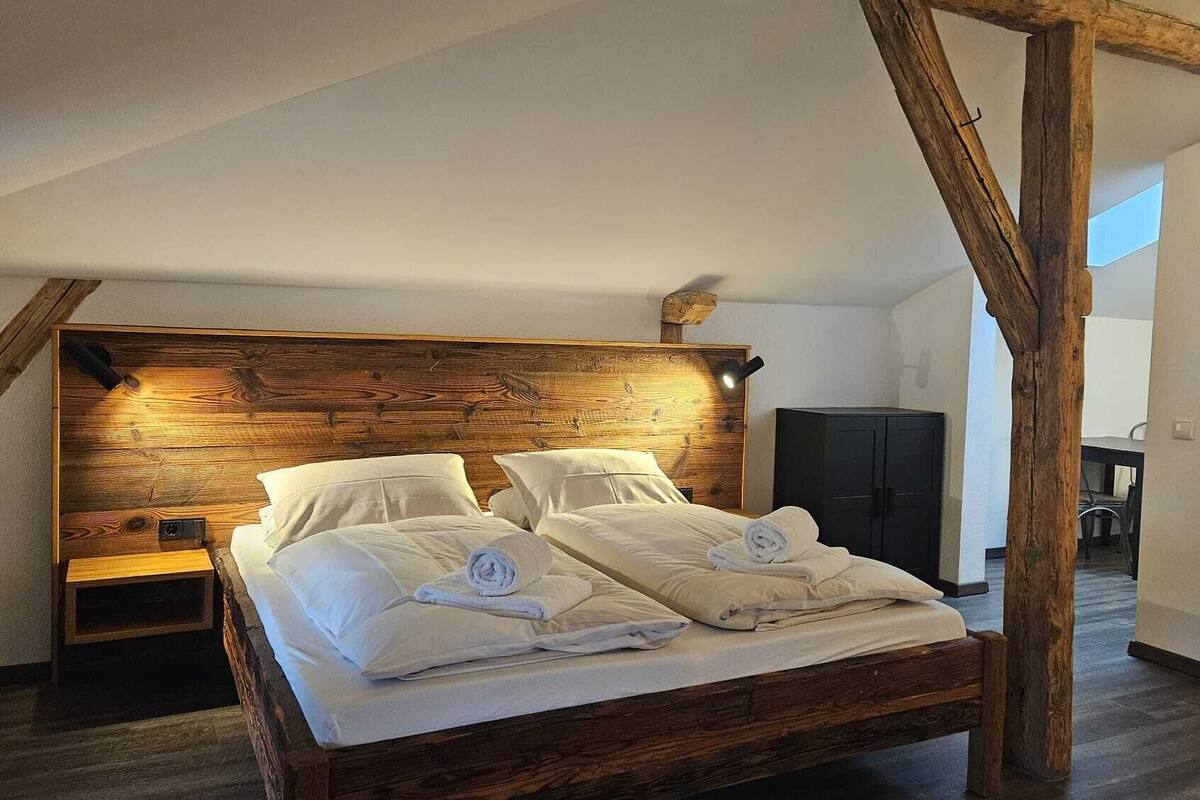 A bedroom with a wooden headboard, two beds, a nightstand, and a wardrobe.