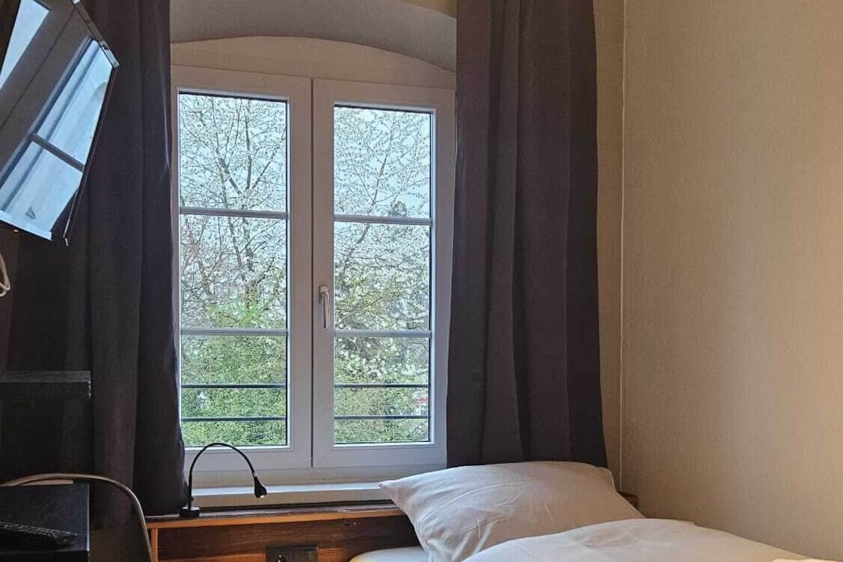 A bedroom with a bed, a desk, and a chair.