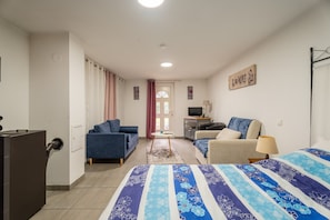 Ein Zimmer mit einem Bett, einem Schlafsofa, einem Schreibtisch, einem Fernseher und einem Fenster mit Vorhängen.