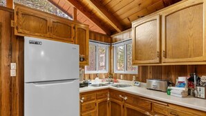 A kitchen with wooden cabinets, a white refrigerator, a sink, and a toaster. - Mama Bear's Cozy Cabin (Sugarloaf)