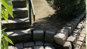 Eine steinerne Treppe führt zu einem Gebäudeeingang, umgeben von Grünpflanzen.