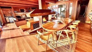 Un amplio salón con chimenea, muebles de madera y una gran mesa de comedor.