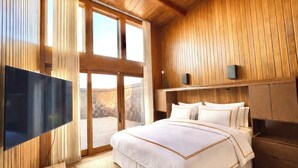 Un dormitorio con una cama grande, televisión, paneles de madera y vistas a través de puertas correderas.