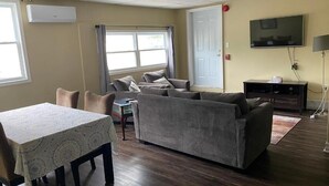A living room with a sofa, a table, and a TV. - Colonial Charm Inn  (Charlottetown)
