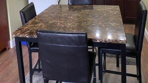 A dining area with a marble table, black chairs, a refrigerator, a coffee maker, and a sink. - Colonial Charm Inn  (Charlottetown)