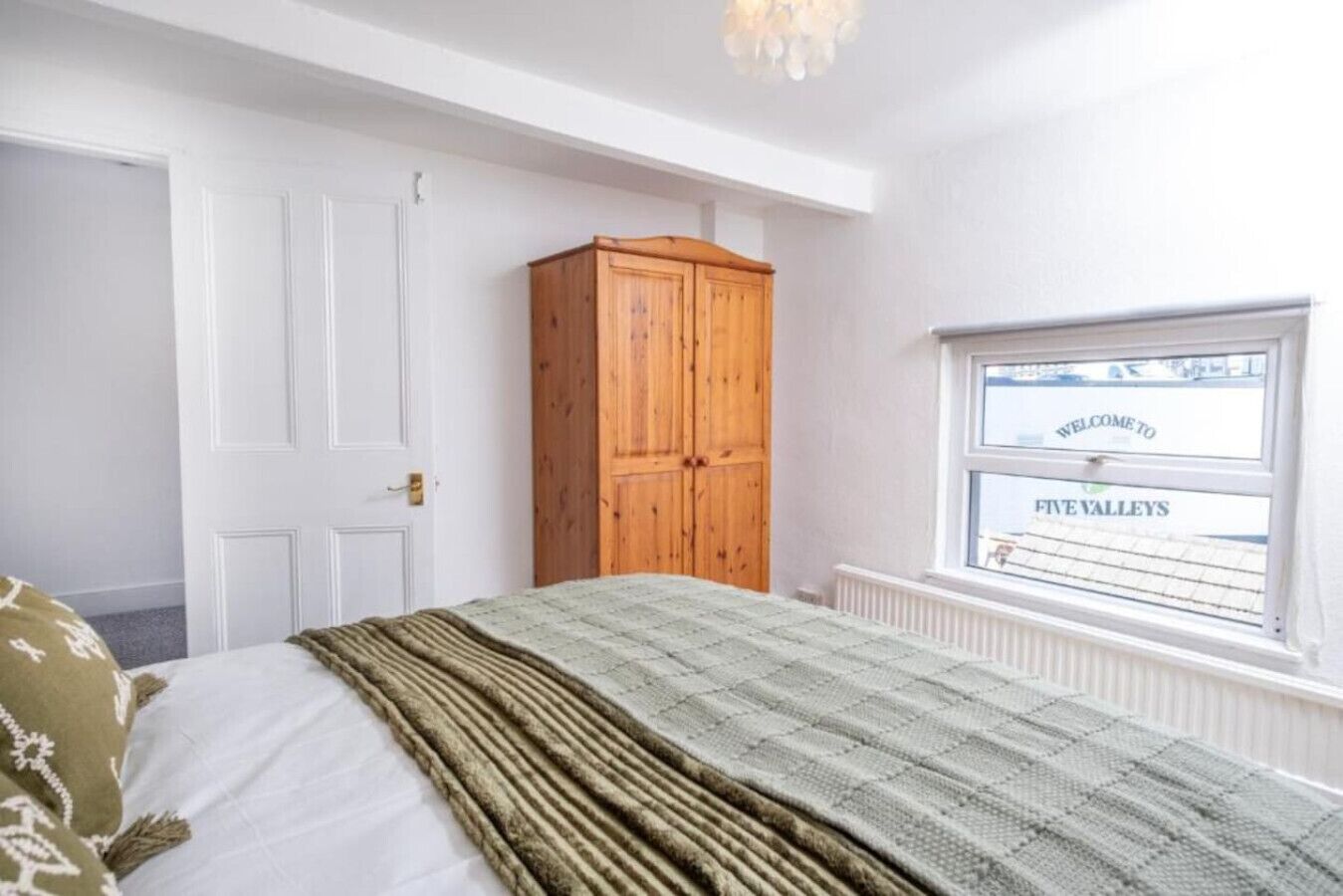 Une chambre à coucher avec un lit, une armoire en bois, une fenêtre donnant sur un beau paysage et un radiateur.