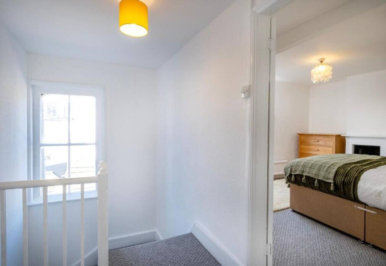 A bedroom with a bed, a dresser, a window, and a door.