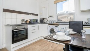 Eine moderne Küche mit weißen Schränken, Backofen, Mikrowelle und Waschmaschine.
