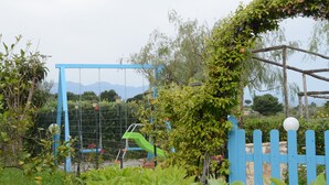 Ein Spielplatz mit blauem Zaun, Klettergerüsten und einem weißen, kugelförmigen Objekt.