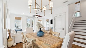 A dining area with a wooden table, chairs, a vase, and a ceiling fan. - Seacrest Beach House with Pool Access (Inlet Beach)