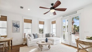 A spacious living room with a white sofa, a round coffee table, and a ceiling fan. - Seacrest Beach House with Pool Access (Inlet Beach)