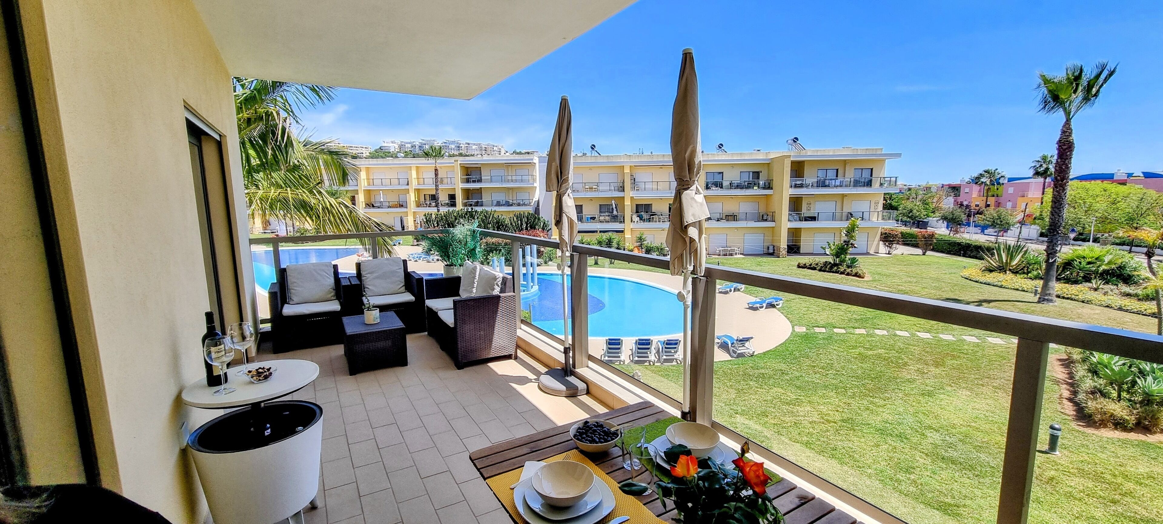 A balcony with a pool view, outdoor seating, and a dining area.