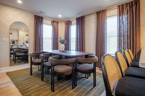 Een eethoek met een rechthoekige tafel, zes stoelen en een vaas met bloemen.