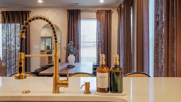 A bathroom with a gold faucet, a mirror, and two bottles of hand soap. - Renovated Spacious Home Near Downtown, Sleeps 10 (Richmond)