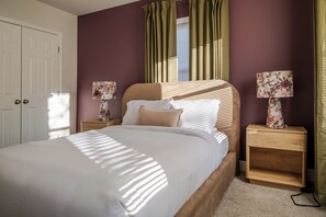 Een slaapkamer met een bed, twee nachtkastjes, een raam met gordijnen en een deur.