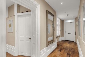 A hallway with white doors, a large mirror, and a wooden floor. - Elegant Soho 2-bed, bright Victorian apartment with lift, walk to Covent Garden (London)