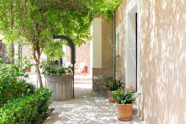 An outdoor patio area with potted plants, a concrete planter, and a table with chairs. - Ca'n Puig de Sòller (Sóller)