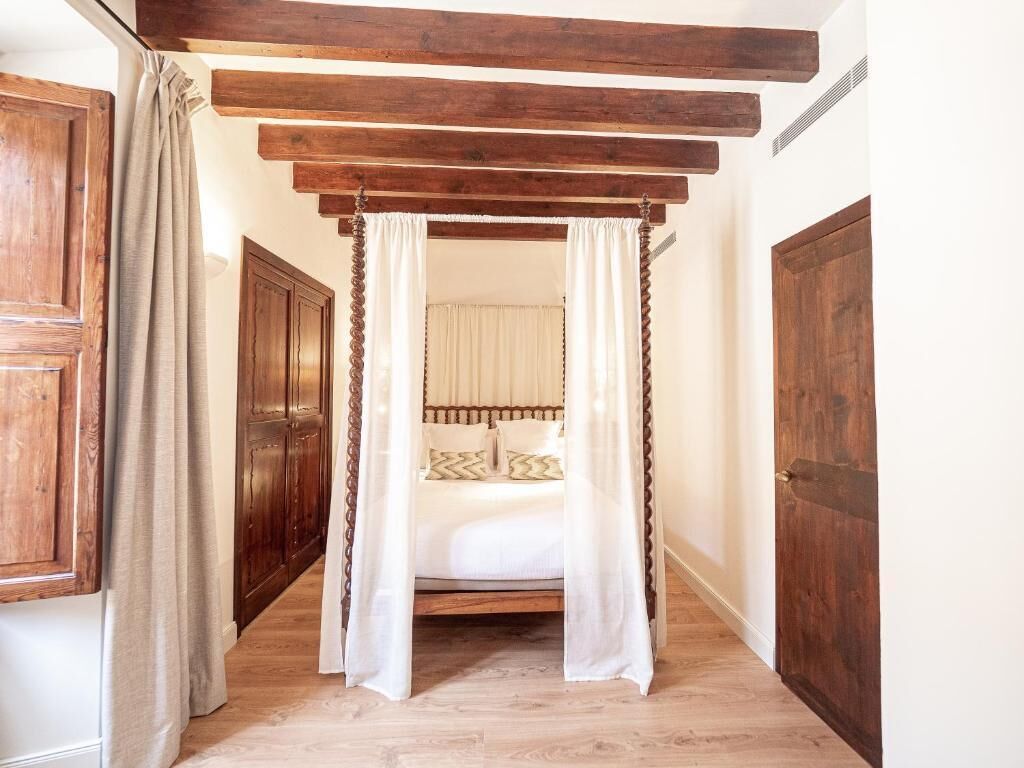 A narrow hallway with a wooden ceiling and a bed with a canopy.