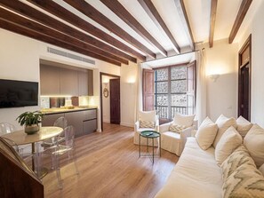 A modern living room with a wooden ceiling, a sofa, a dining table with chairs, and a kitchen area. - Ca'n Puig de Sòller (Sóller)