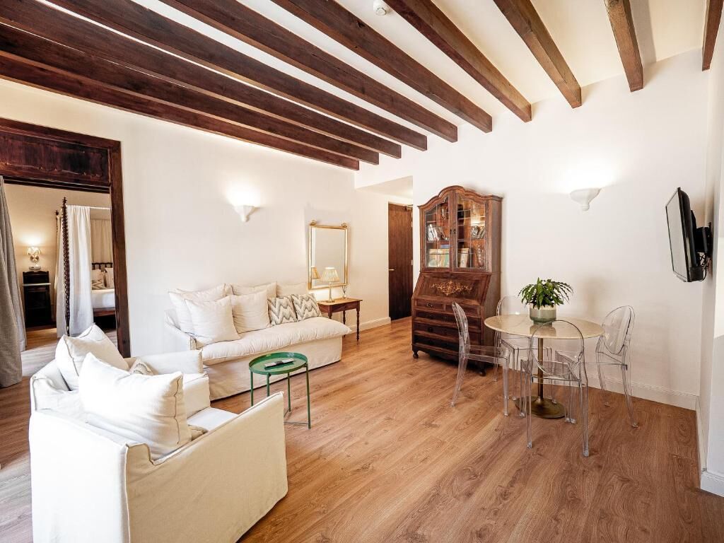 A living room with a sofa, a coffee table, a wooden cabinet, and a dining area with chairs.