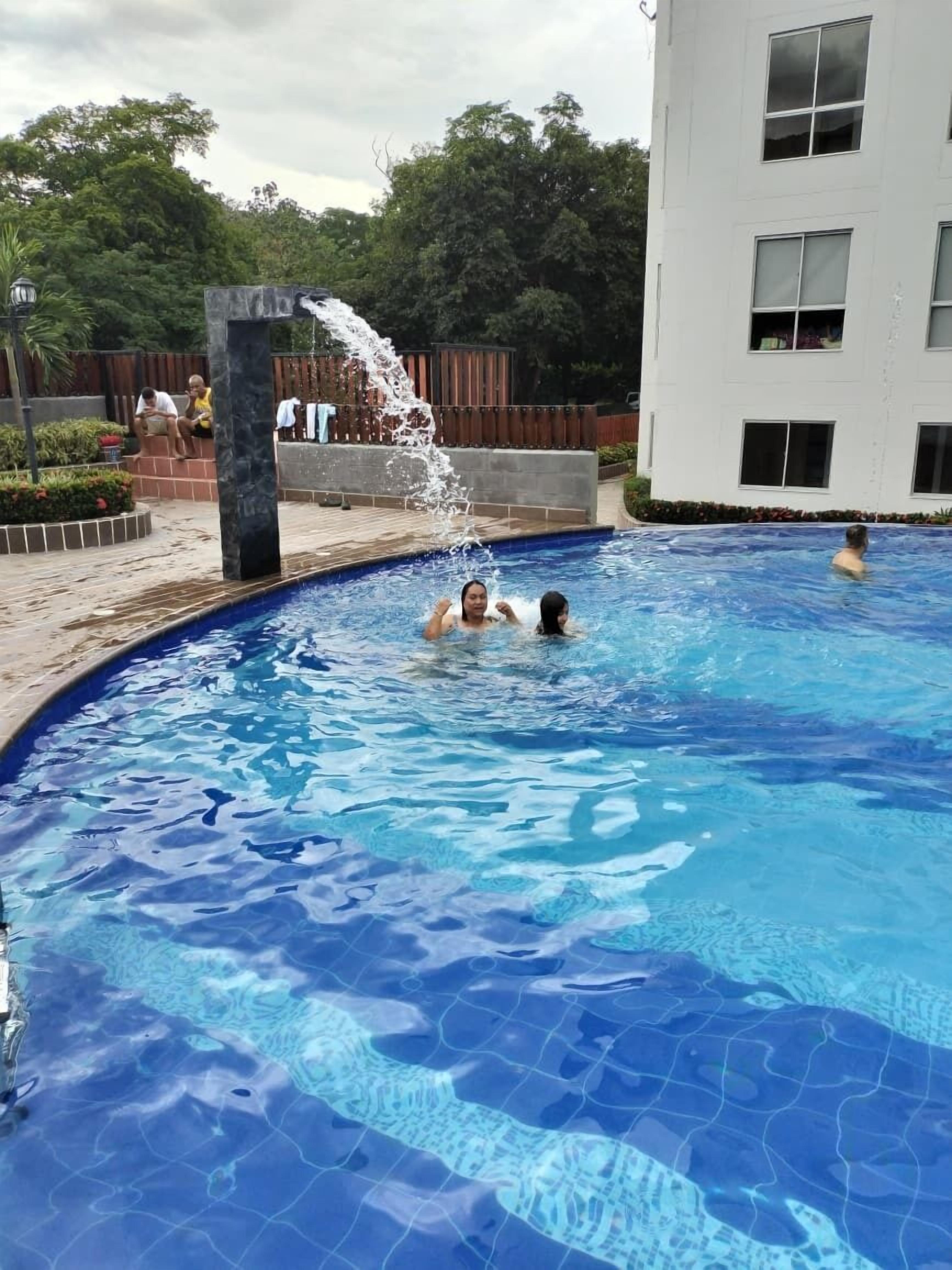 Una piscina con agua cristalina, rodeada por una terraza de madera y un edificio blanco.