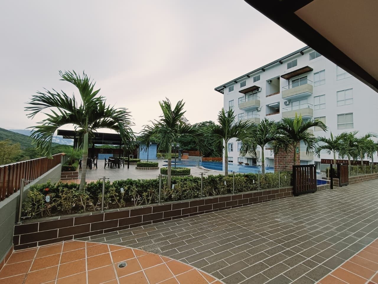 Ein Wohngebäude mit Schwimmbad, Palmen und einer überdachten Terrasse.