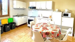 Una cocina con armarios blancos, estufa a gas, microondas y una mesa de comedor con sillas.