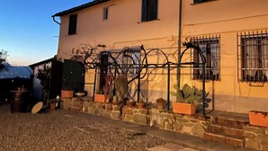 Un edificio con fachada de piedra, varias ventanas con contraventanas y un camino de entrada de grava.