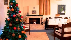 A cozy living room with a fireplace, a Christmas tree, and a bed. - Xenon Achladokampos (Argos-Mykines)