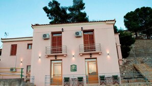 A pink building with two balconies, a stone staircase, and a green sign. - Xenon Achladokampos (Argos-Mykines)