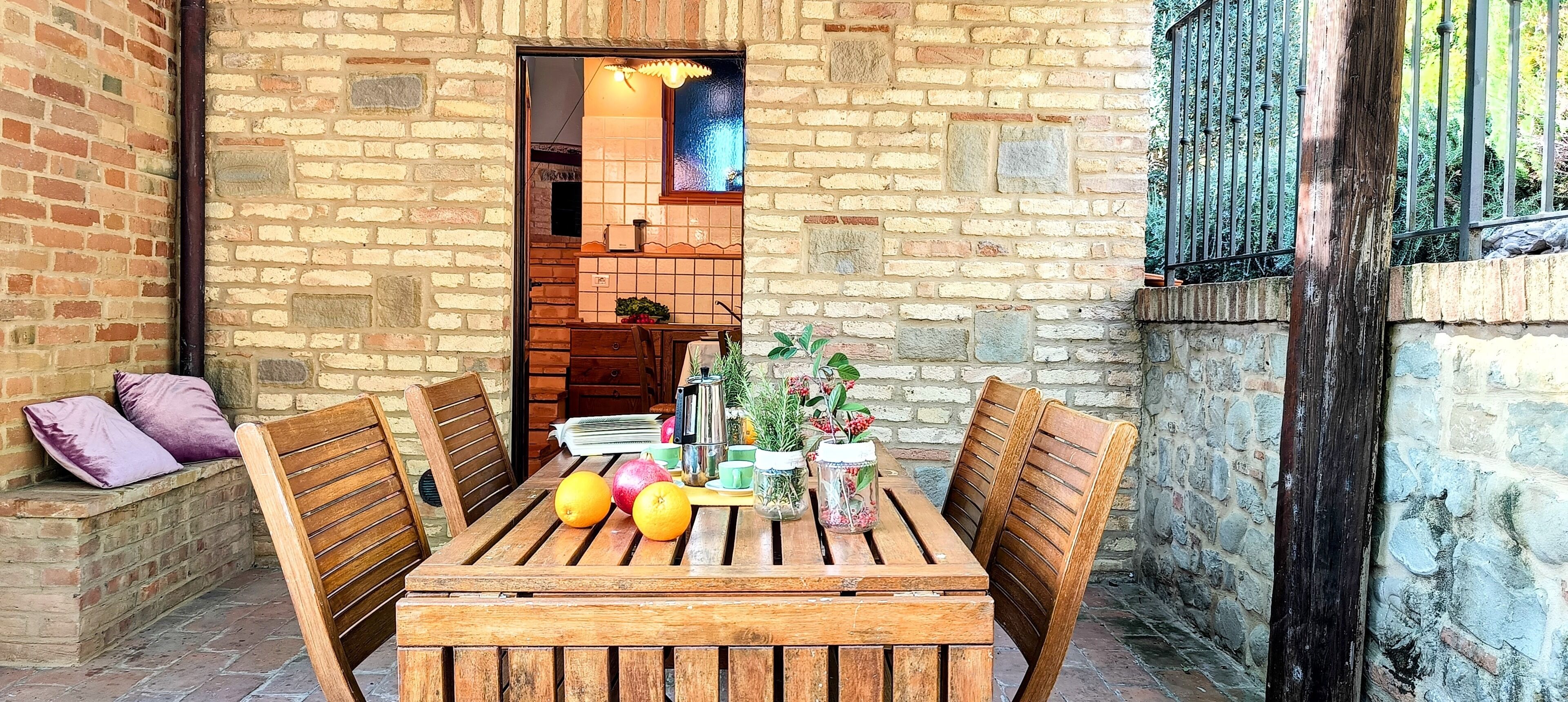 Una mesa de madera con sillas, un muro de ladrillo y una ventana con vistas.