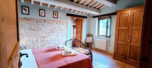 A room with a brick wall, wooden door, and a table with a red tablecloth. - VILLA IL RIGOGOLO - Private Pool in the Hills of the Marche Region (Sant'Angelo in Pontano)