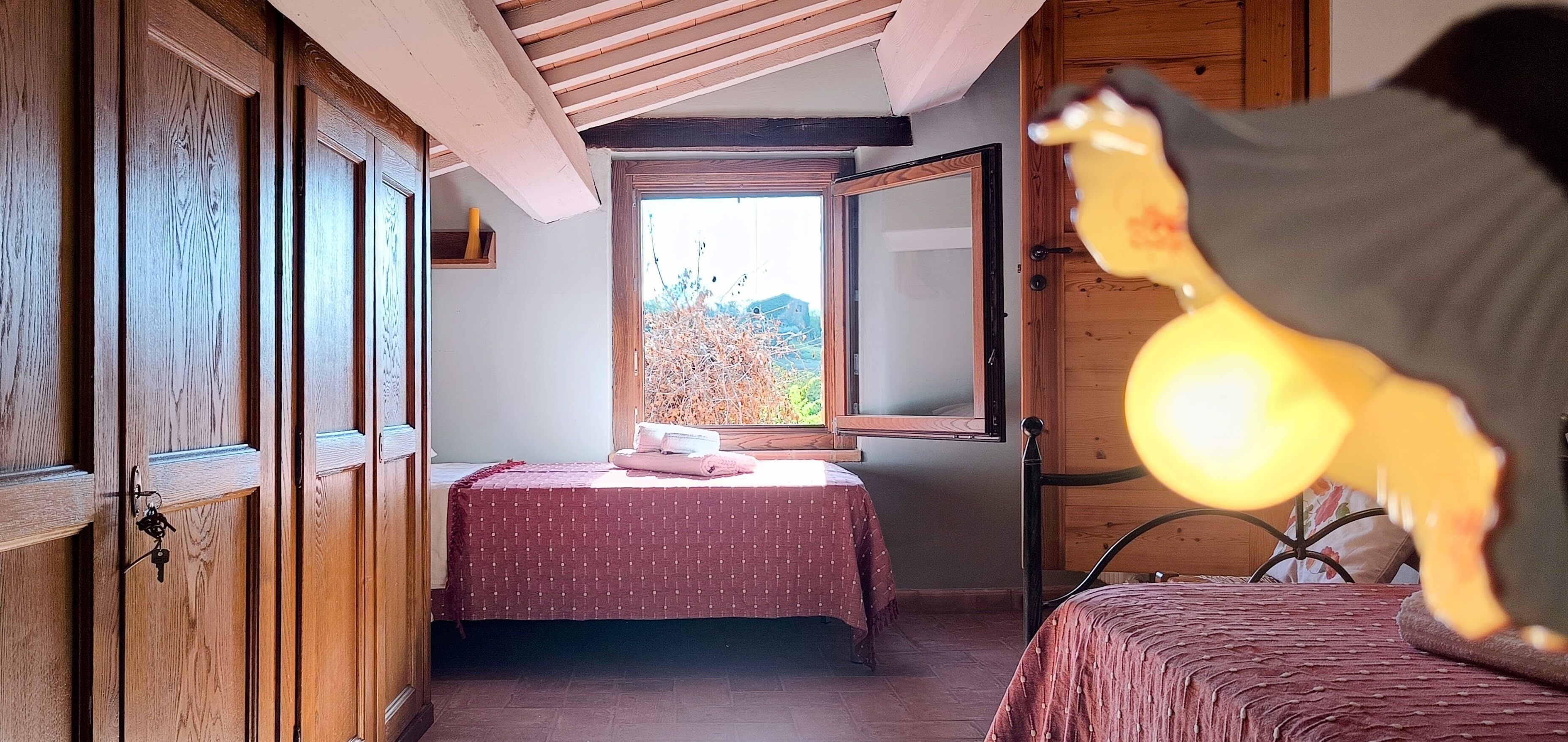 Un dormitorio con una cama, una ventana y un armario de madera.
