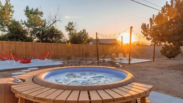 Un bain à remous entouré d’une terrasse en bois avec des sièges, d’une clôture en bois et d’arbres.